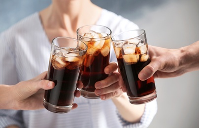 Photo of Friends with glasses of cold cola on color background, closeup