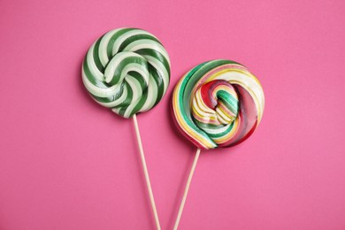Photo of Sticks with colorful lollipops on pink background, flat lay