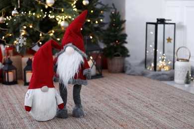 Cute Scandinavian gnomes on carpet near Christmas tree indoors