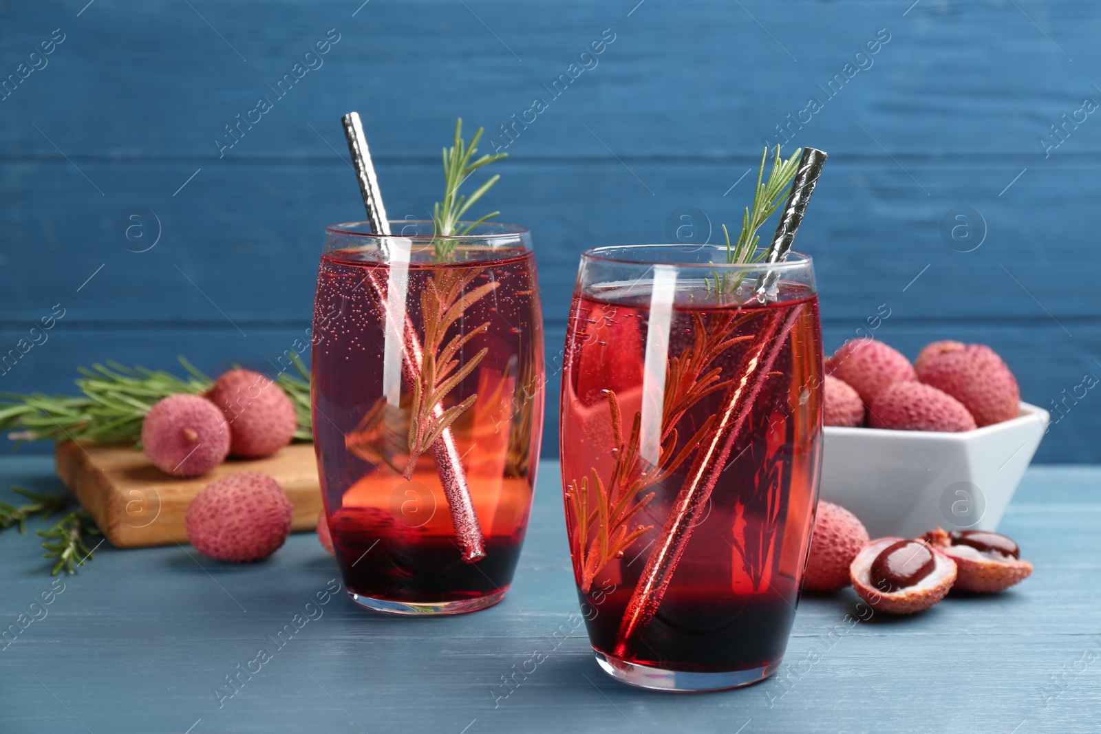 Photo of Lychee cocktail with rosemary on light blue table