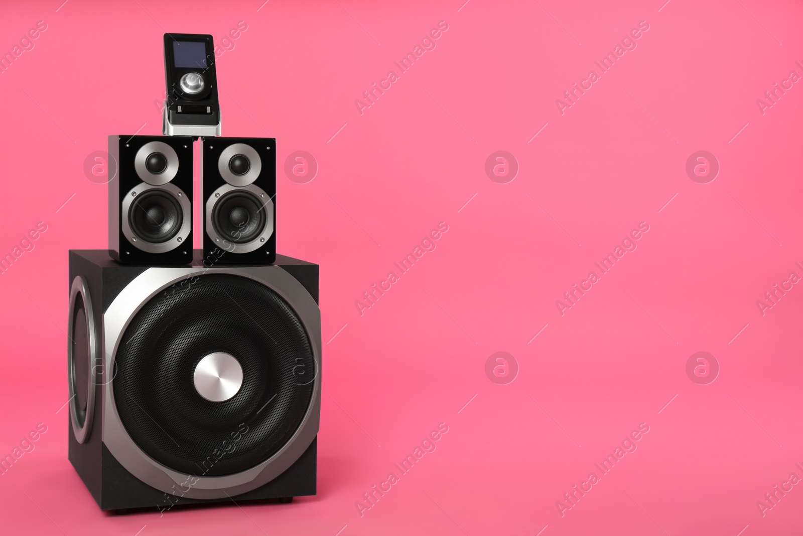 Photo of Modern powerful audio speaker system with remote on pink background, space for text