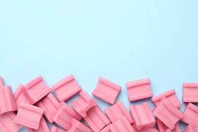 Photo of Tasty pink chewing gums on light blue background, flat lay. Space for text