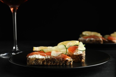 Delicious bruschettas with salmon served on black table