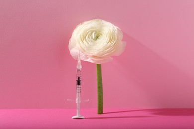 Photo of Cosmetology. Medical syringe and ranunculus flower on pink background