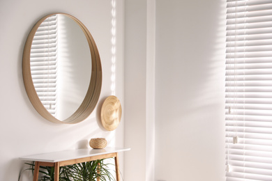 Photo of Stylish round mirror hanging on white wall in room