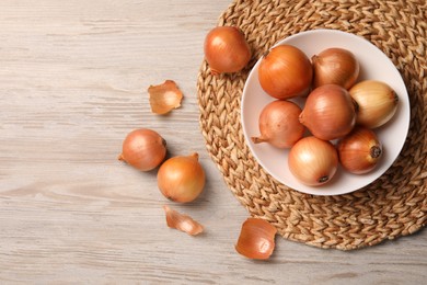 Photo of Many ripe onions on wooden table, flat lay. Space for text