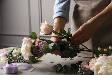 Photo of Florist creating beautiful bouquet at light grey table indoors, closeup