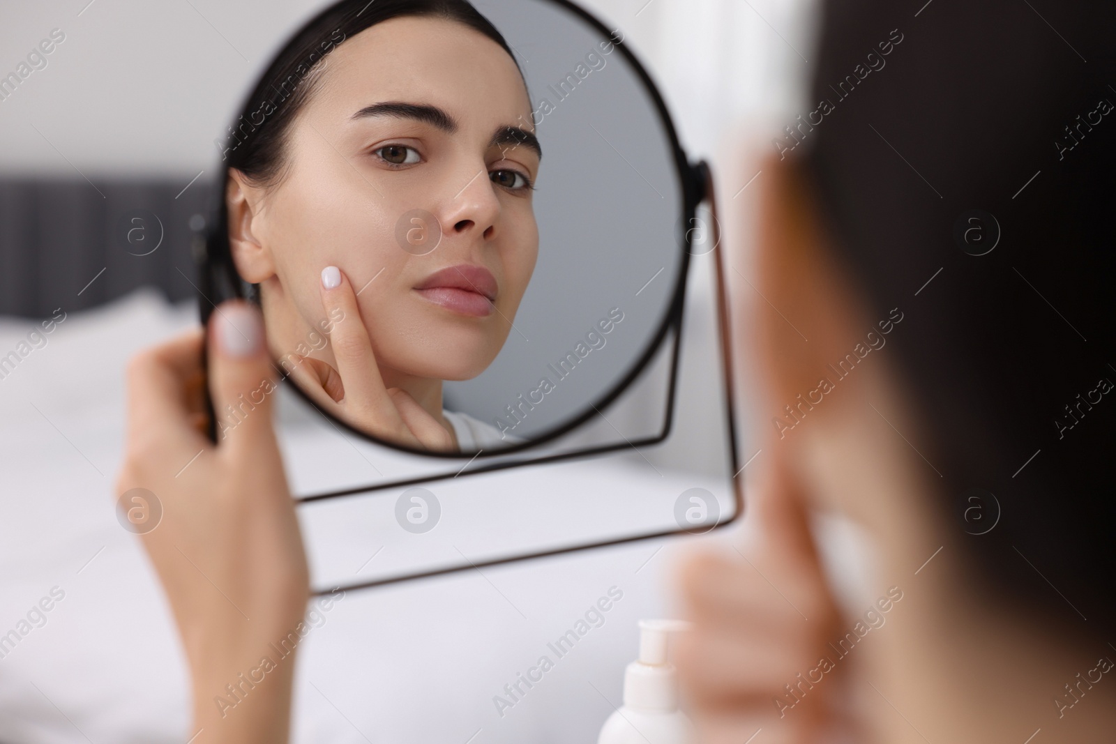 Photo of Woman with dry skin looking at mirror indoors
