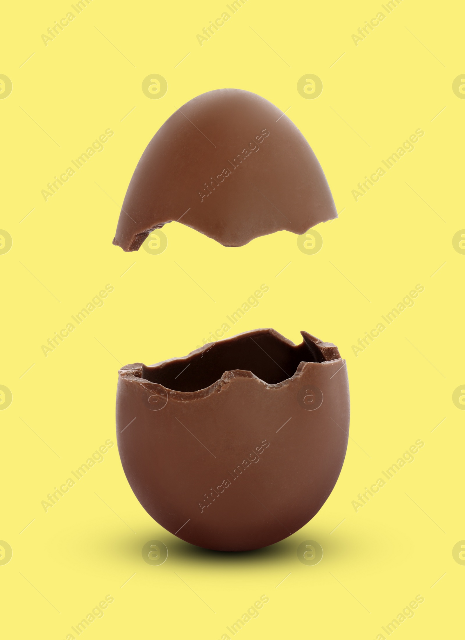 Image of Broken milk chocolate egg on yellow background