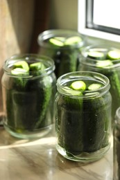 Glass jars with fresh cucumbers on table, closeup. Canning vegetables