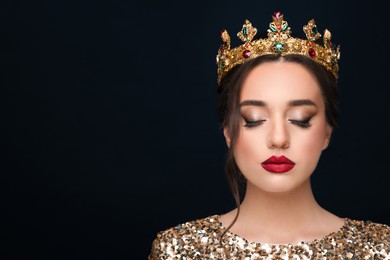 Beautiful young woman wearing luxurious crown on black background, space for text
