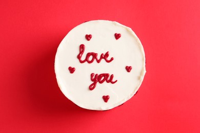 Photo of Bento cake with text Love You on red table, top view. St. Valentine's day surprise