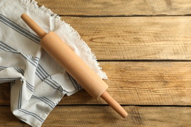 Rolling pin and kitchen towel on wooden table, top view. Space for text