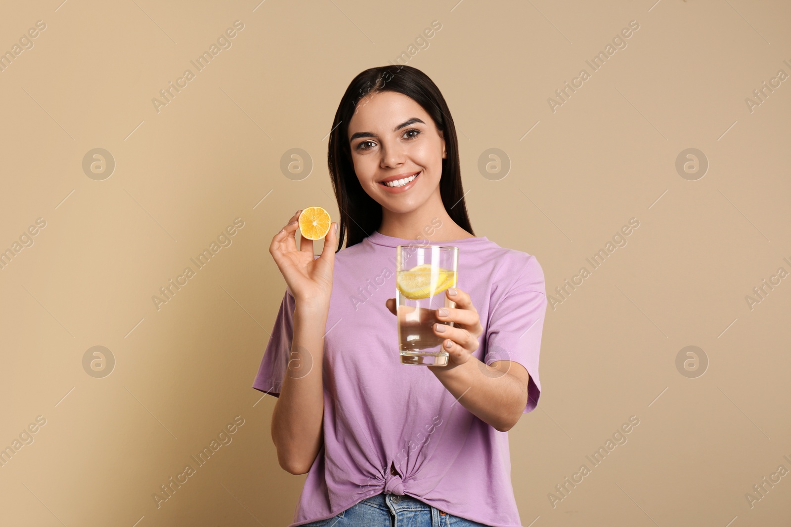 Photo of Beautiful young woman with tasty lemon water and fresh fruit on beige background