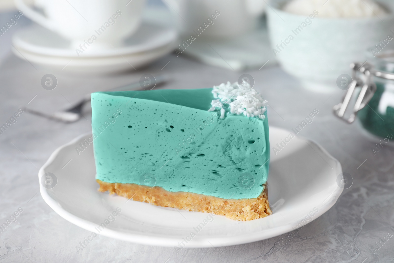 Photo of Piece of tasty spirulina cheesecake on grey table, closeup view