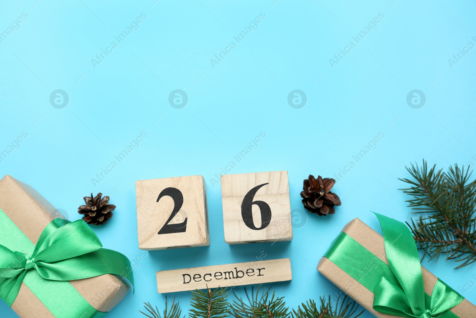 Photo of Flat lay composition with block calendar and gifts on light blue background, space for text. Boxing day concept