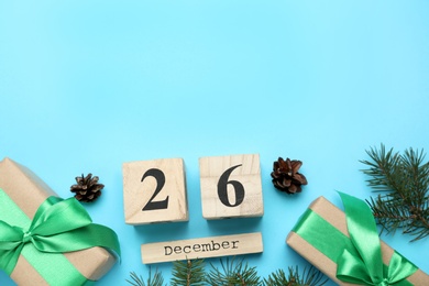 Photo of Flat lay composition with block calendar and gifts on light blue background, space for text. Boxing day concept