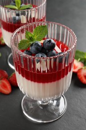 Photo of Delicious panna cotta with fruit coulis and fresh berries on dark grey table