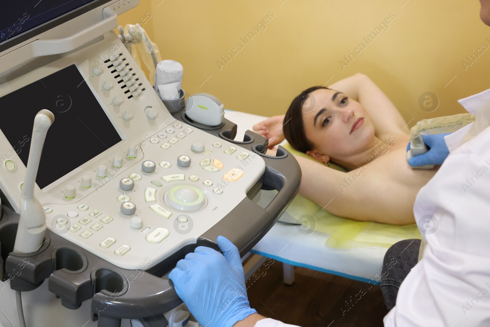 Photo of Mammologist conducting ultrasound examination of woman's breast in clinic, closeup