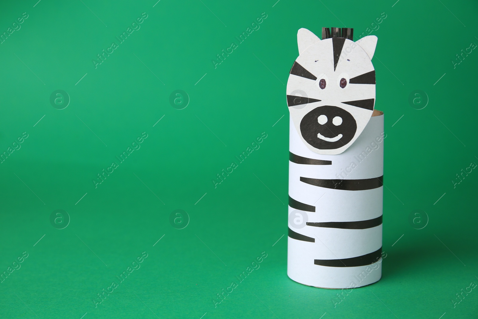 Photo of Toy zebra made from toilet paper hub on green background, space for text. Children's handmade ideas