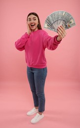 Happy woman with dollar banknotes on pink background