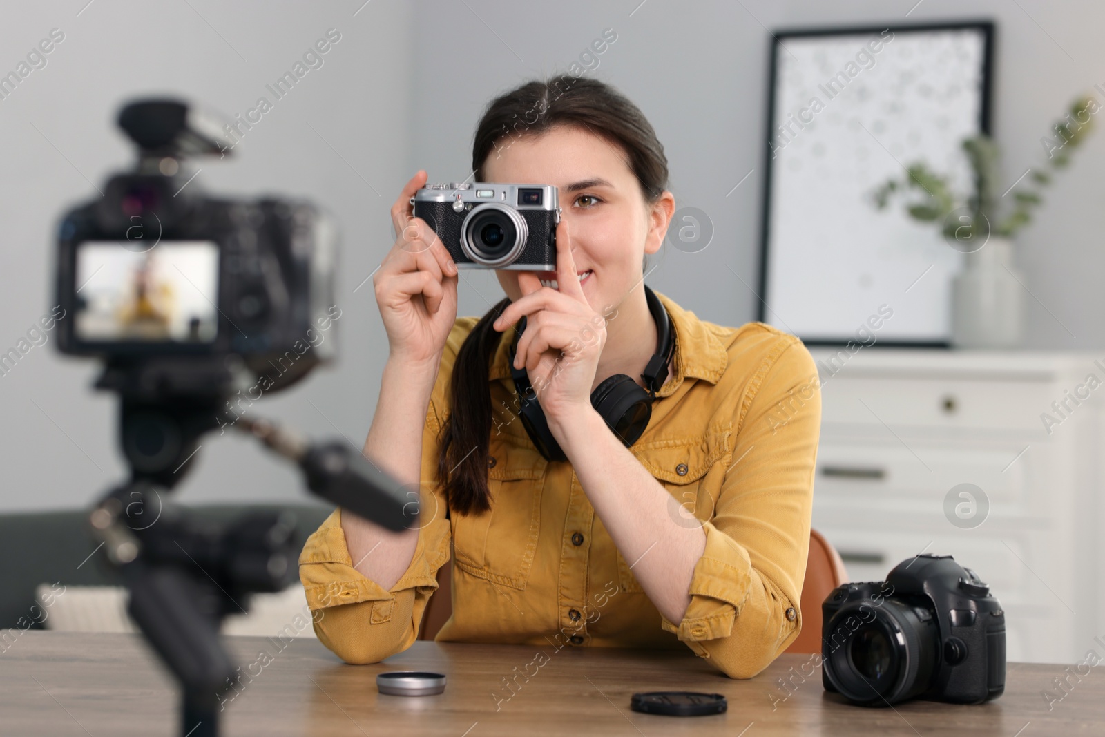 Photo of Smiling technology blogger recording video review about cameras at home