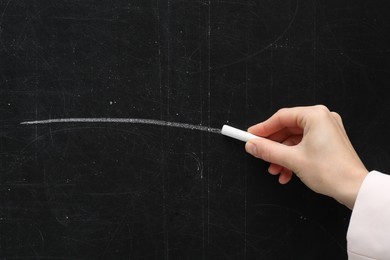 Photo of Teacher writing with chalk on black chalkboard, closeup. Space for text