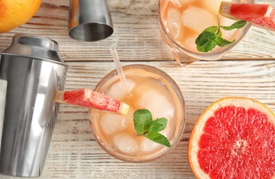 Flat lay composition with glasses of grapefruit cocktails on wooden table