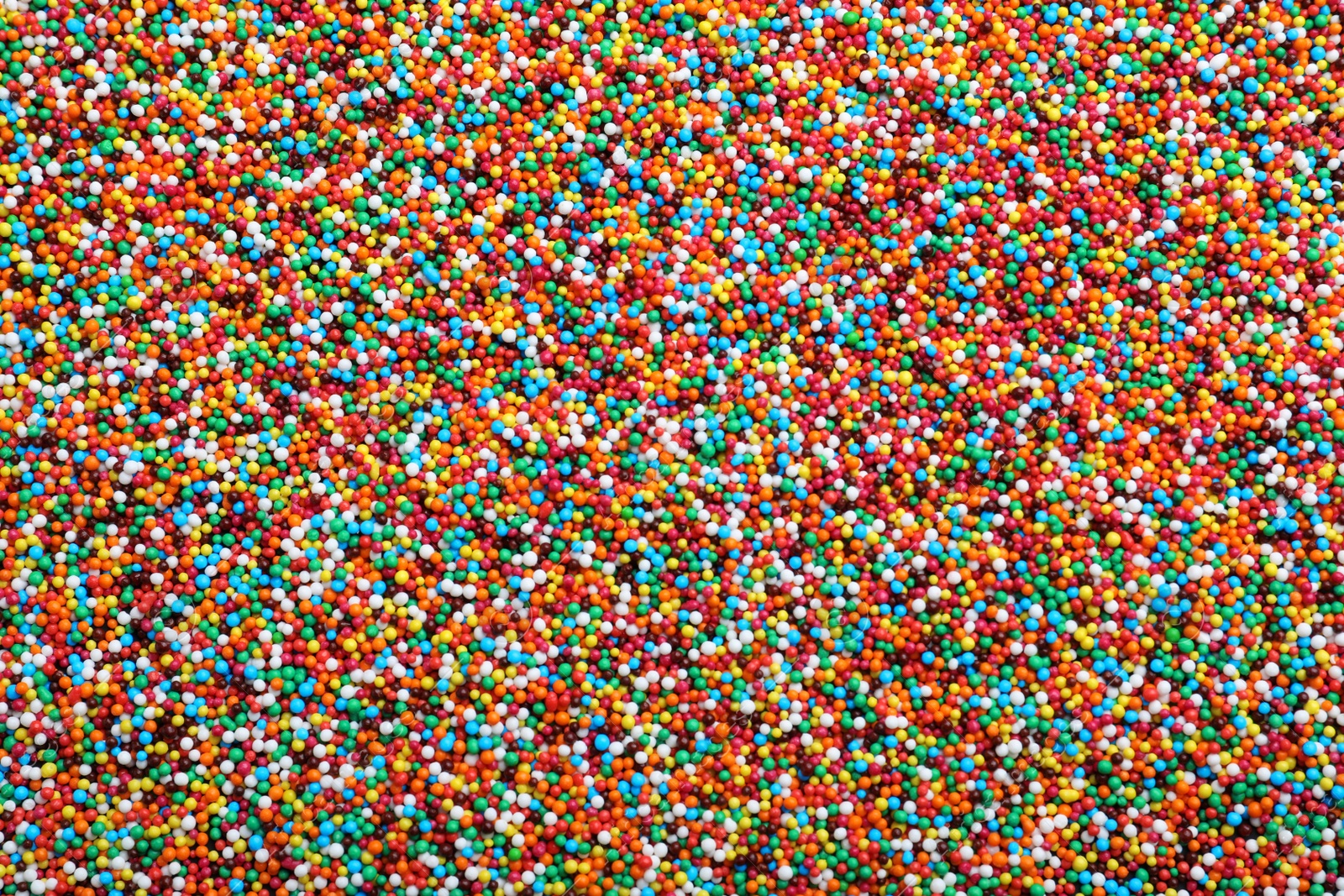 Photo of Bright colorful sprinkles as background, top view. Confectionery decor