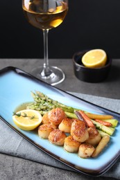 Photo of Delicious fried scallops with asparagus served on grey table