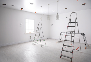 Photo of Empty room with stretch ceiling and ladders