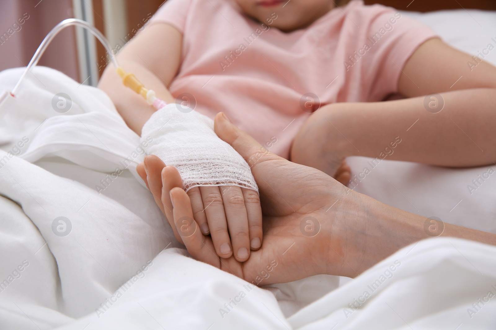 Photo of Doctor holding little child's hand with intravenous drip in hospital, closeup