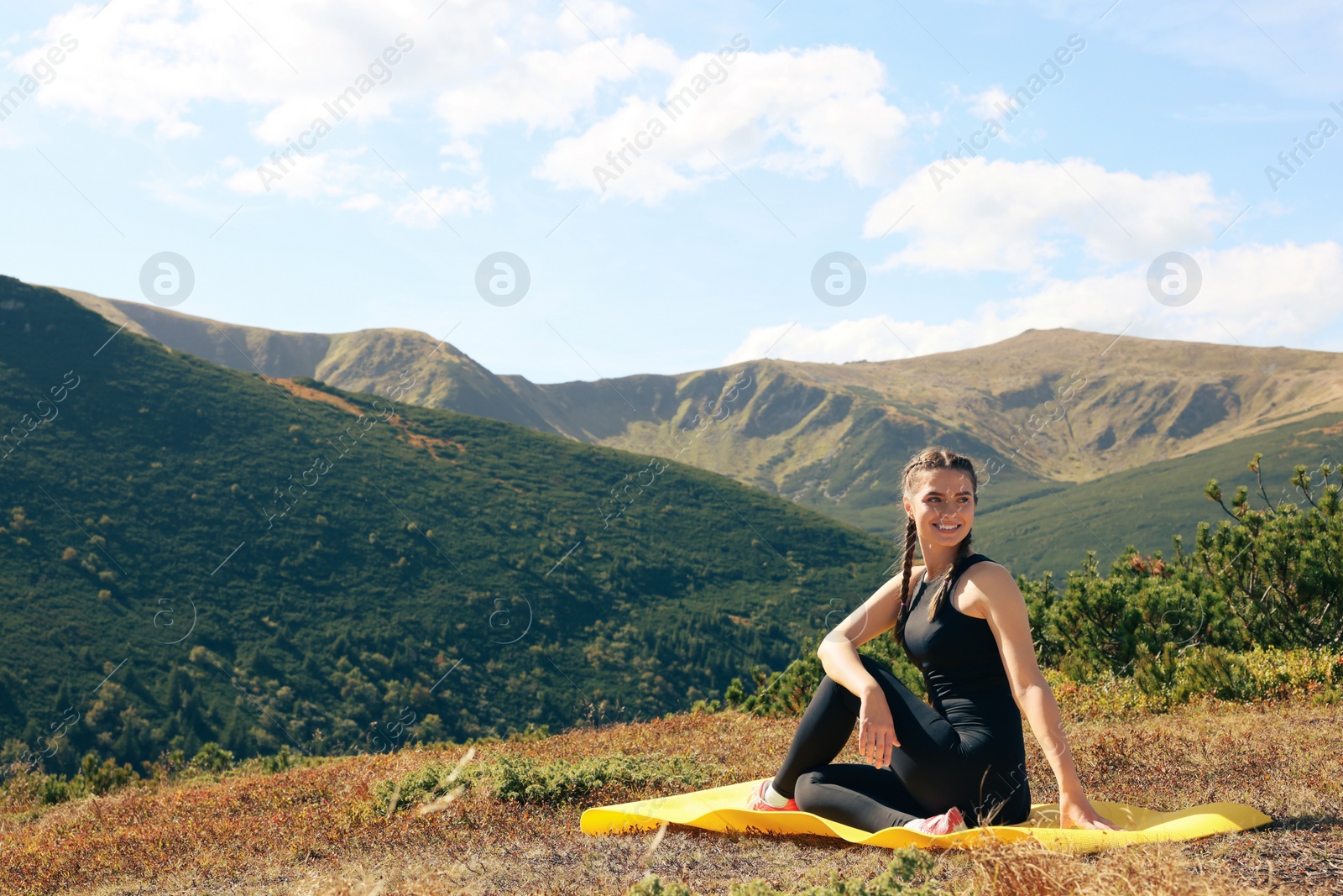 Photo of Beautiful young woman practicing yoga in mountains on summer morning