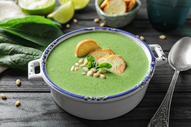 Photo of Bowl of healthy green soup with fresh spinach on grey wooden table