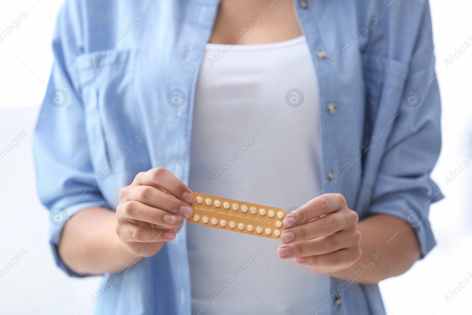 Photo of Young woman with birth control pills on light background. Gynecology