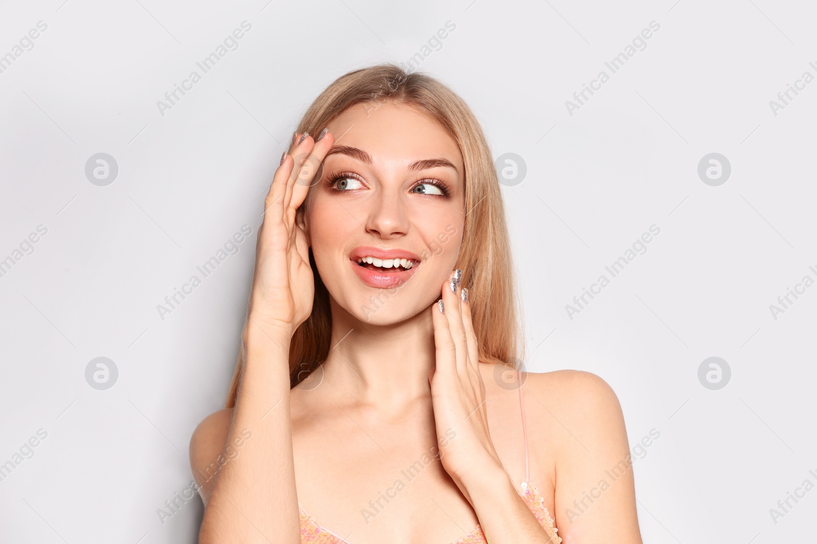 Photo of Portrait of beautiful young woman with shiny manicure on light background. Nail polish trends