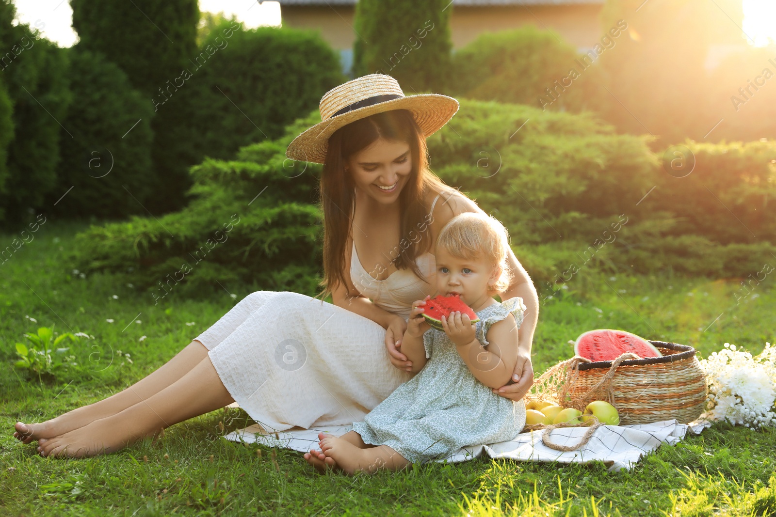 Photo of Mother with her baby daughter having picnic in garden on sunny day