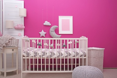 Photo of Baby room interior with crib near color wall