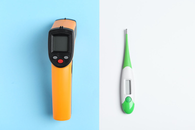 Non-contact infrared and digital thermometers on color background, flat lay