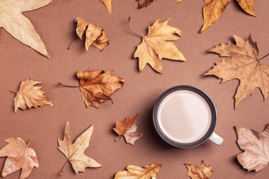 Photo of Flat lay composition with hot cozy drink and autumn leaves on color background