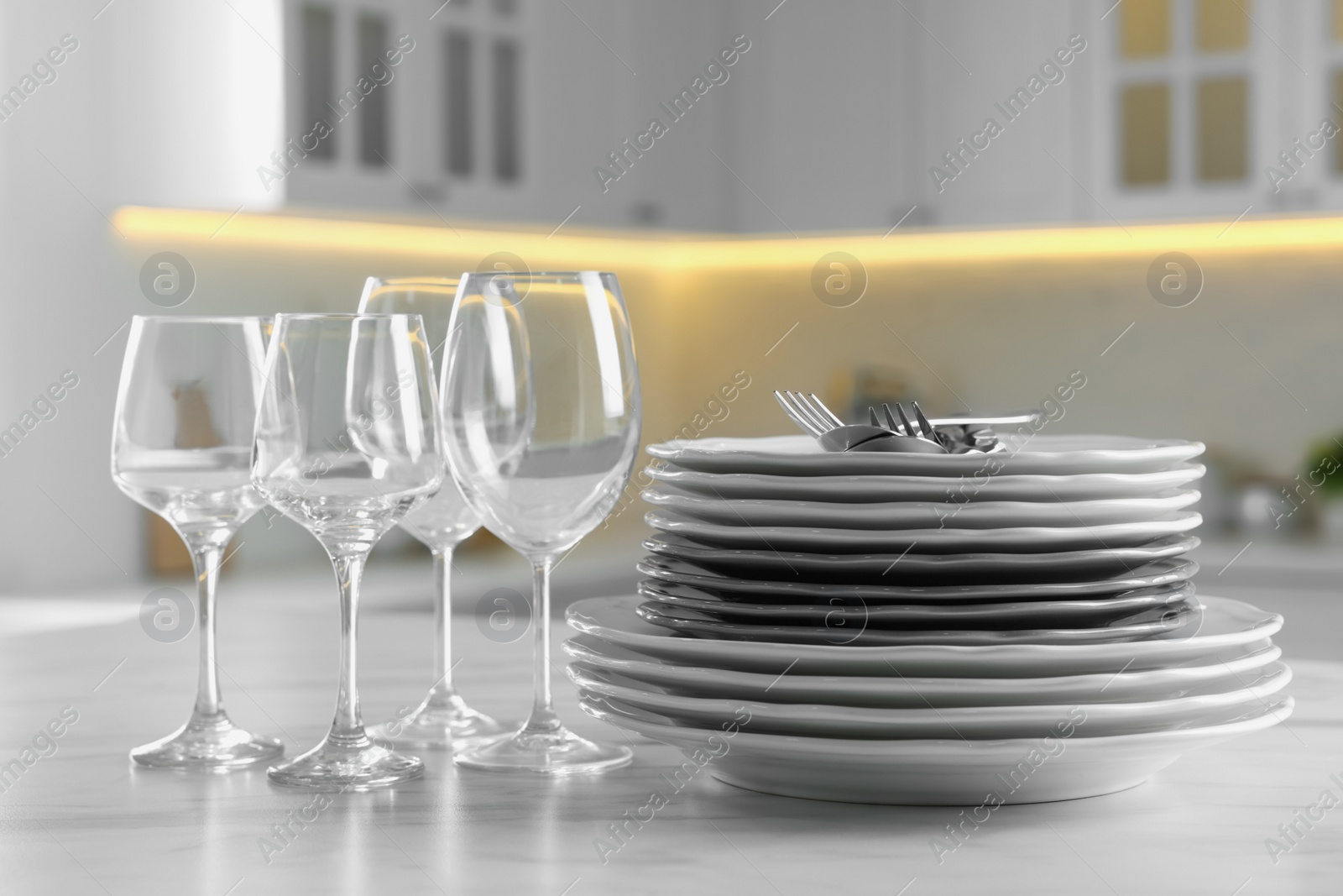 Photo of Different clean dishware, cutlery and glasses on white marble table in kitchen