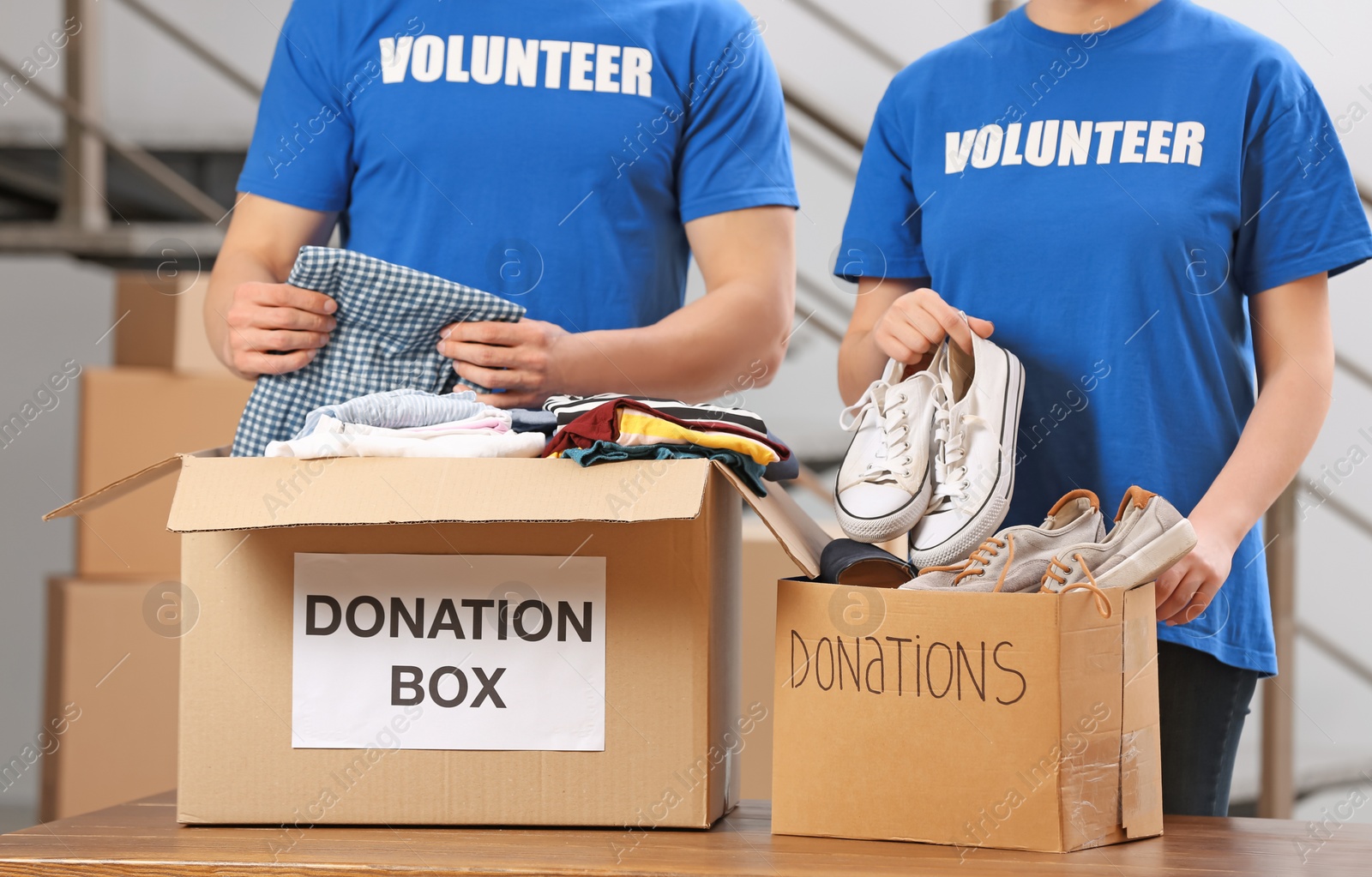 Photo of Volunteers putting clothes and shoes in donation boxes indoors