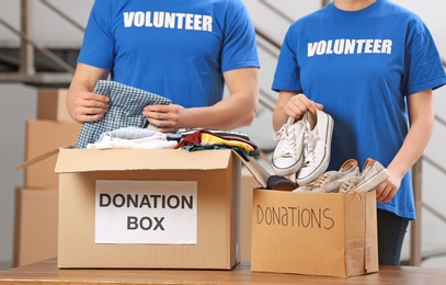 Volunteers putting clothes and shoes in donation boxes indoors