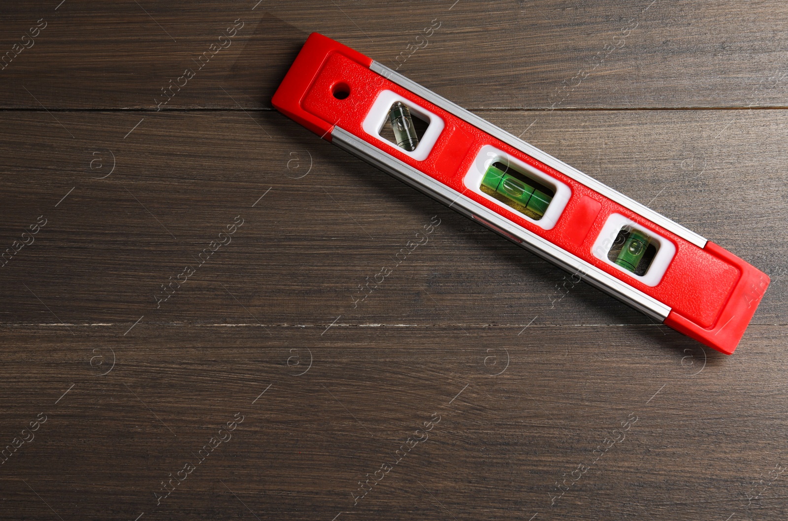 Photo of Red building level on wooden table, top view. Space for text