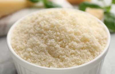 Photo of Bowl with grated parmesan cheese on light table, closeup