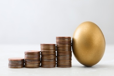 Gold egg and stacks of coins on table