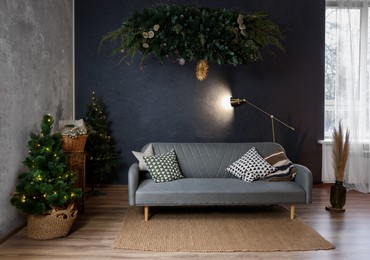 Photo of Stylish living room with comfortable sofa and Christmas trees. Interior design