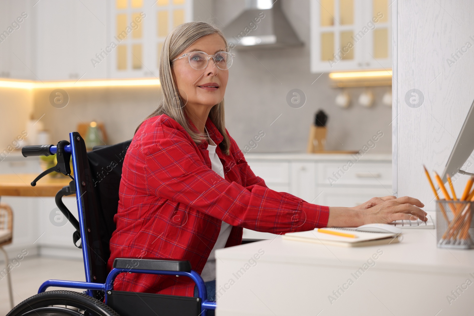 Photo of Woman in wheelchair using computer at table in home office