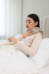 Photo of Sick young woman with box of tissues in bed at home
