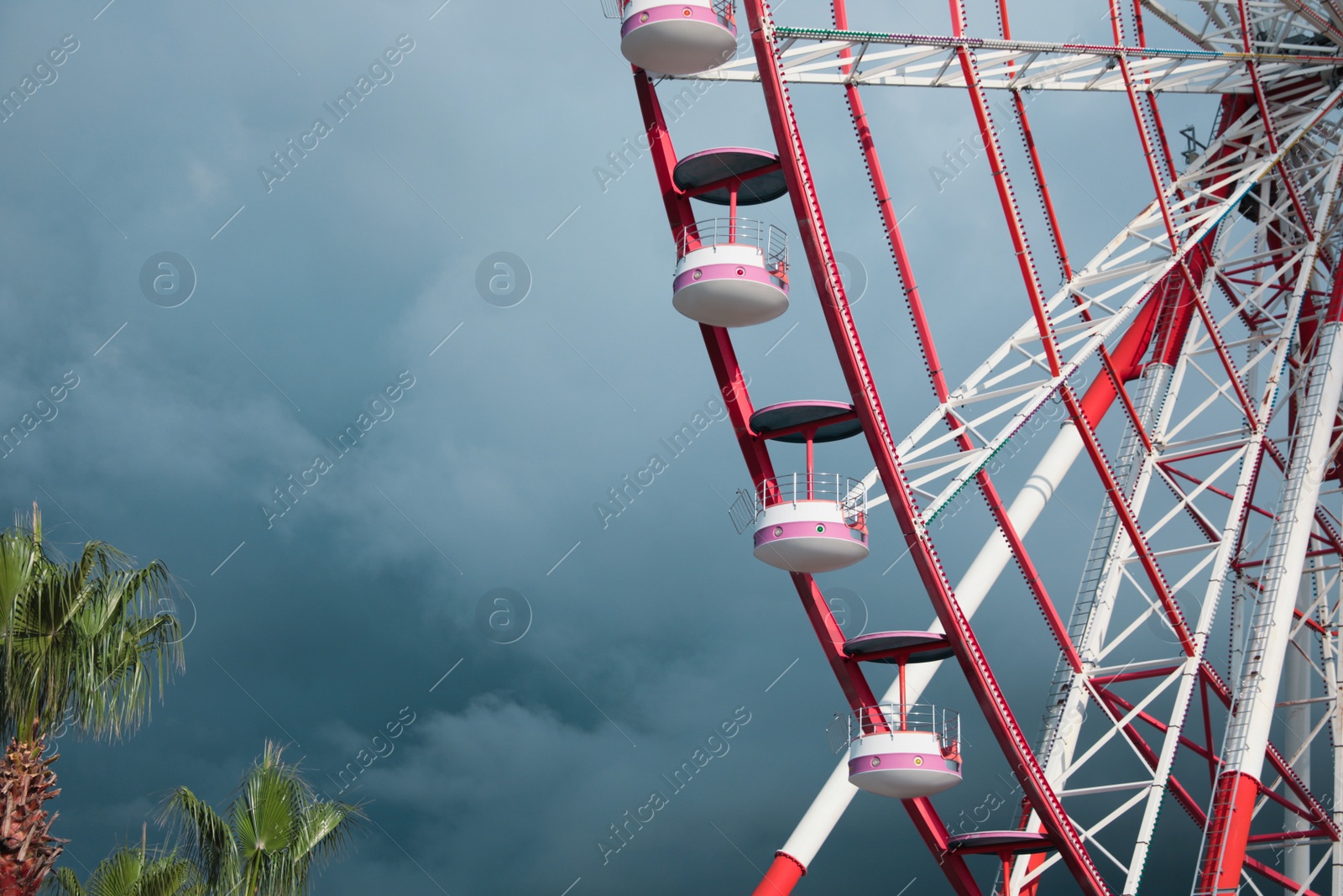 Photo of Beautiful large Ferris wheel against heavy rainy clouds outdoors. Space for text